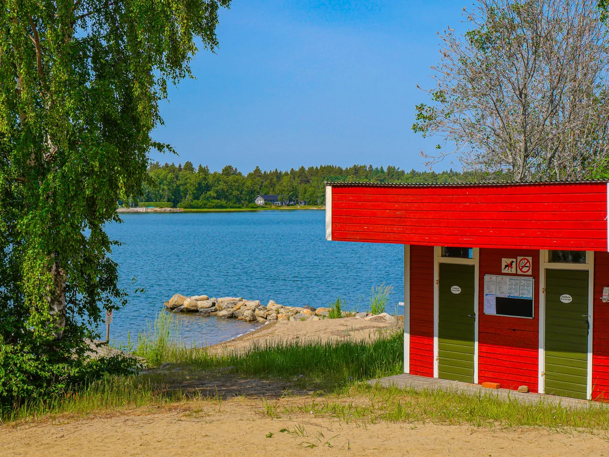 Rote Hütte mit Umkleidekabinen am Strand in Finnland