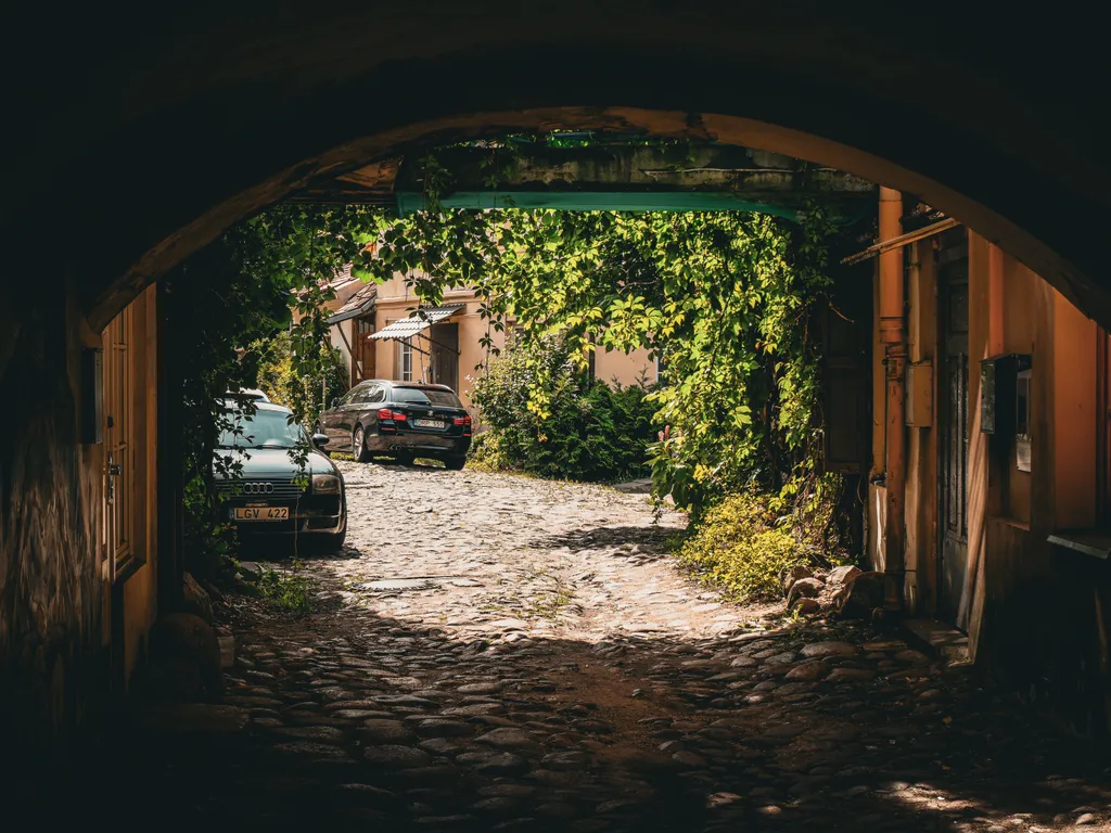 Dunkle Durchfahrt in einen hellen, grünen Hinterhof