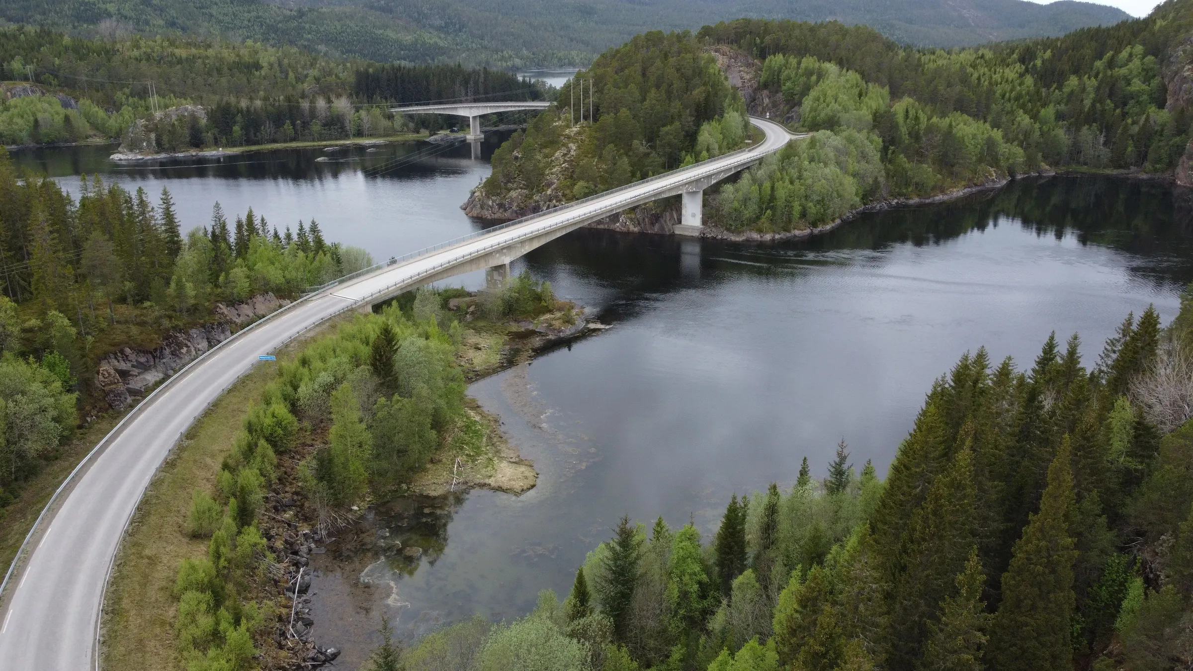 Eine Straße führt über zwei Brücken durch die grünen, baumbedeckten Inseln an der norwegischen Küste