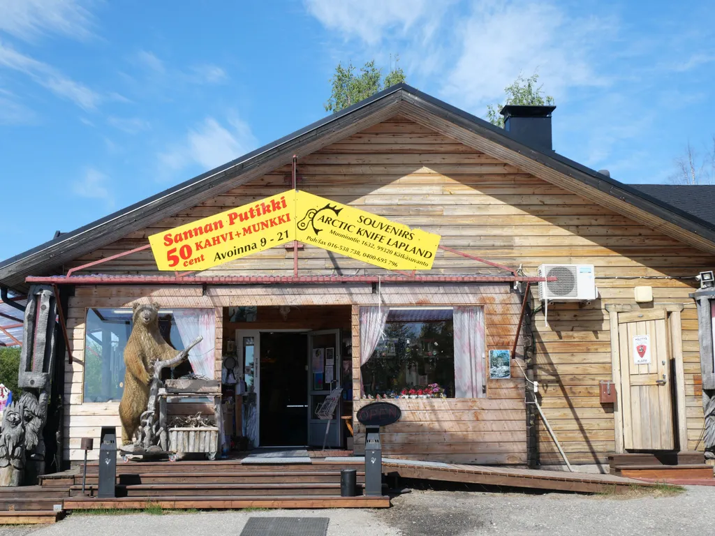 Ein Haus aus Holz vor welchem auf der Veranda ein ausgestopfter Bär steht.