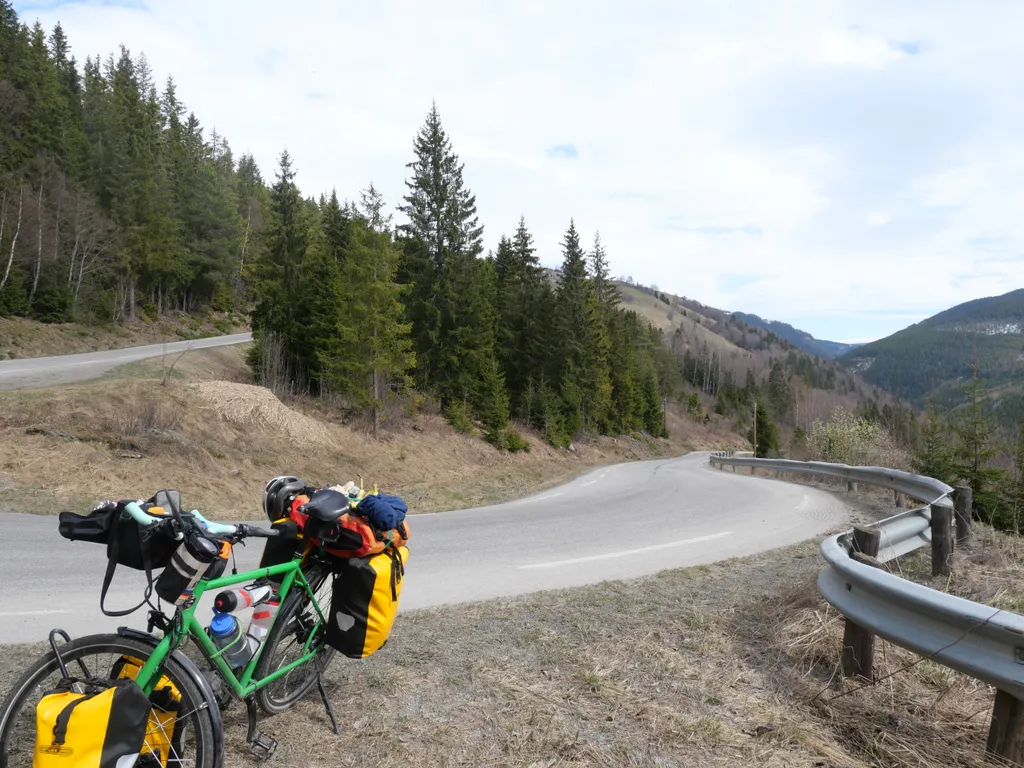 Mein Fahrrad steht an einer Kurve der Serpentinen die durch einen Nadelwald nach oben führt.